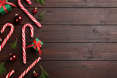 Photo of Flat lay composition with candy canes and Christmas decor on wooden table. Space for text