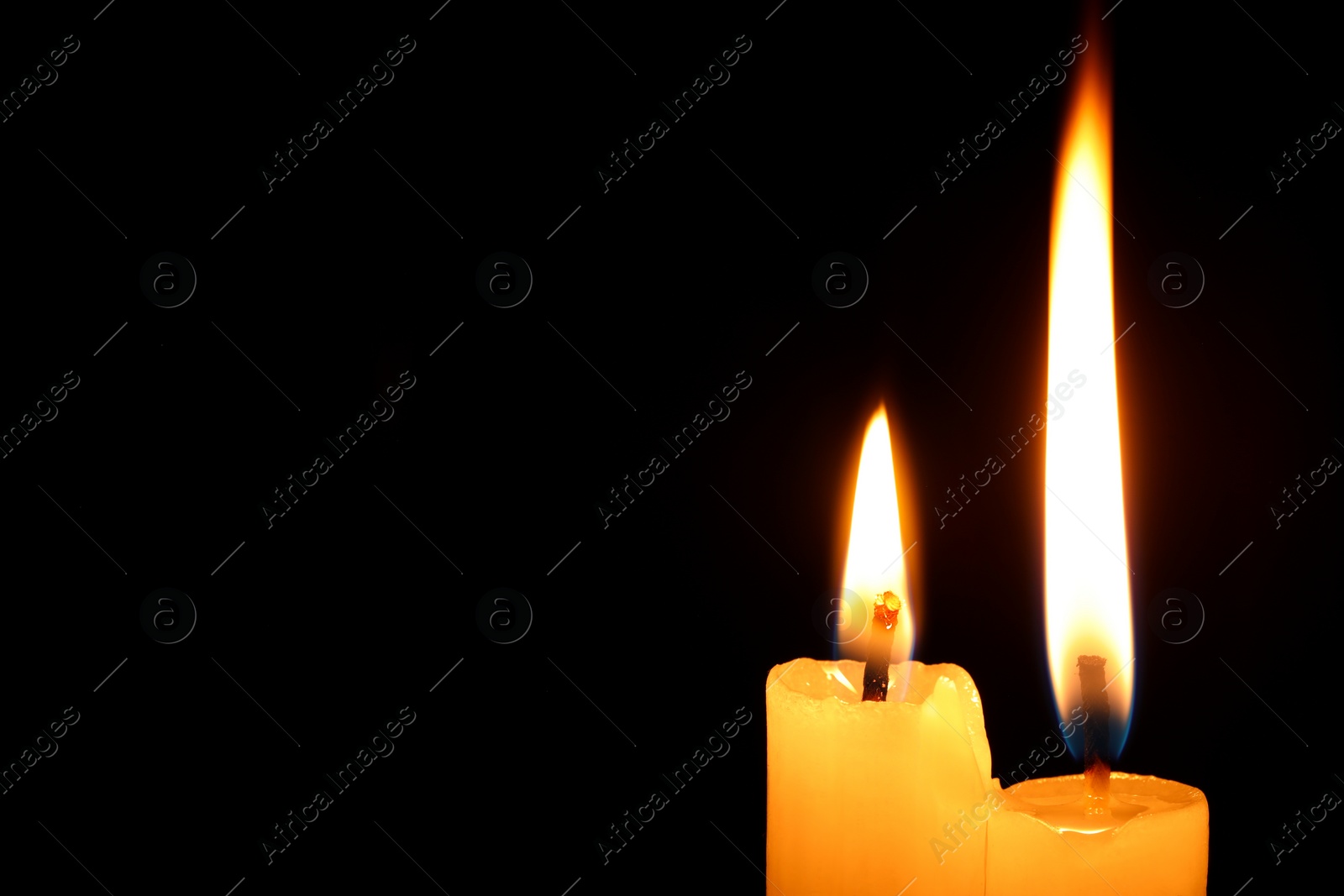 Photo of Burning candles on black background, closeup. Space for text