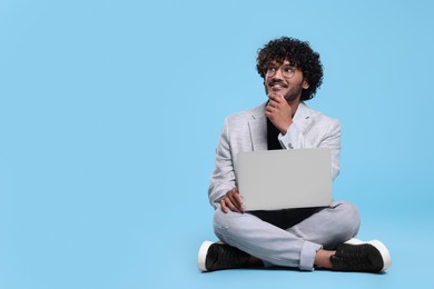 Photo of Smiling man with laptop on light blue background, space for text