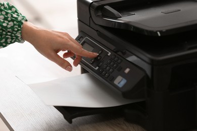 Photo of Woman using modern printer in office, closeup