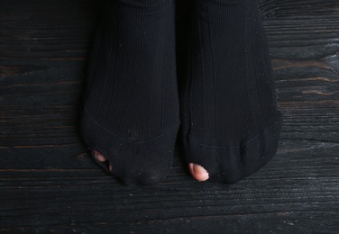 Photo of Poor person in shabby socks on wooden floor, closeup