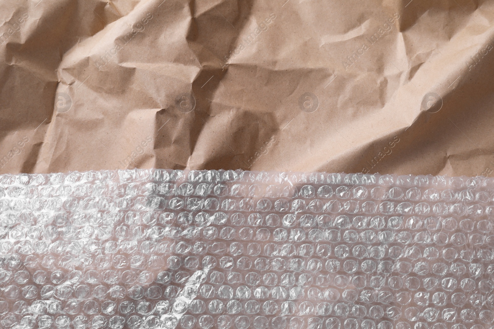 Photo of Transparent bubble wrap on kraft paper, top view. Space for text