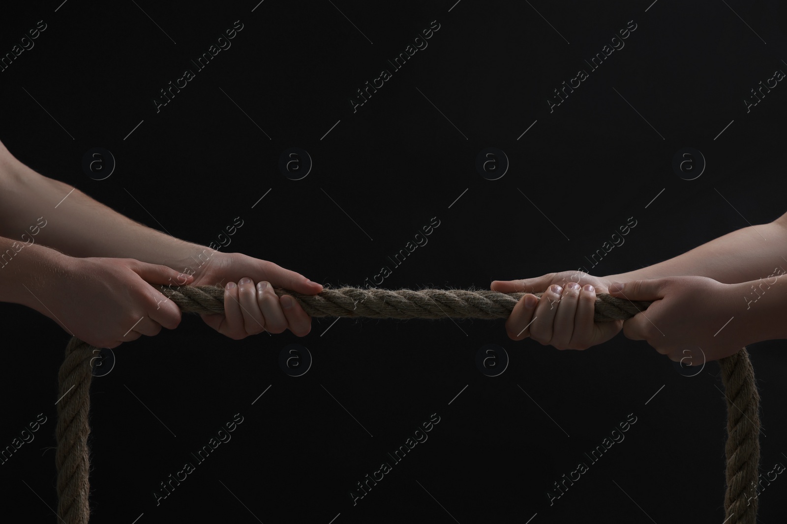 Photo of Dispute concept. Men pulling rope on black background, closeup