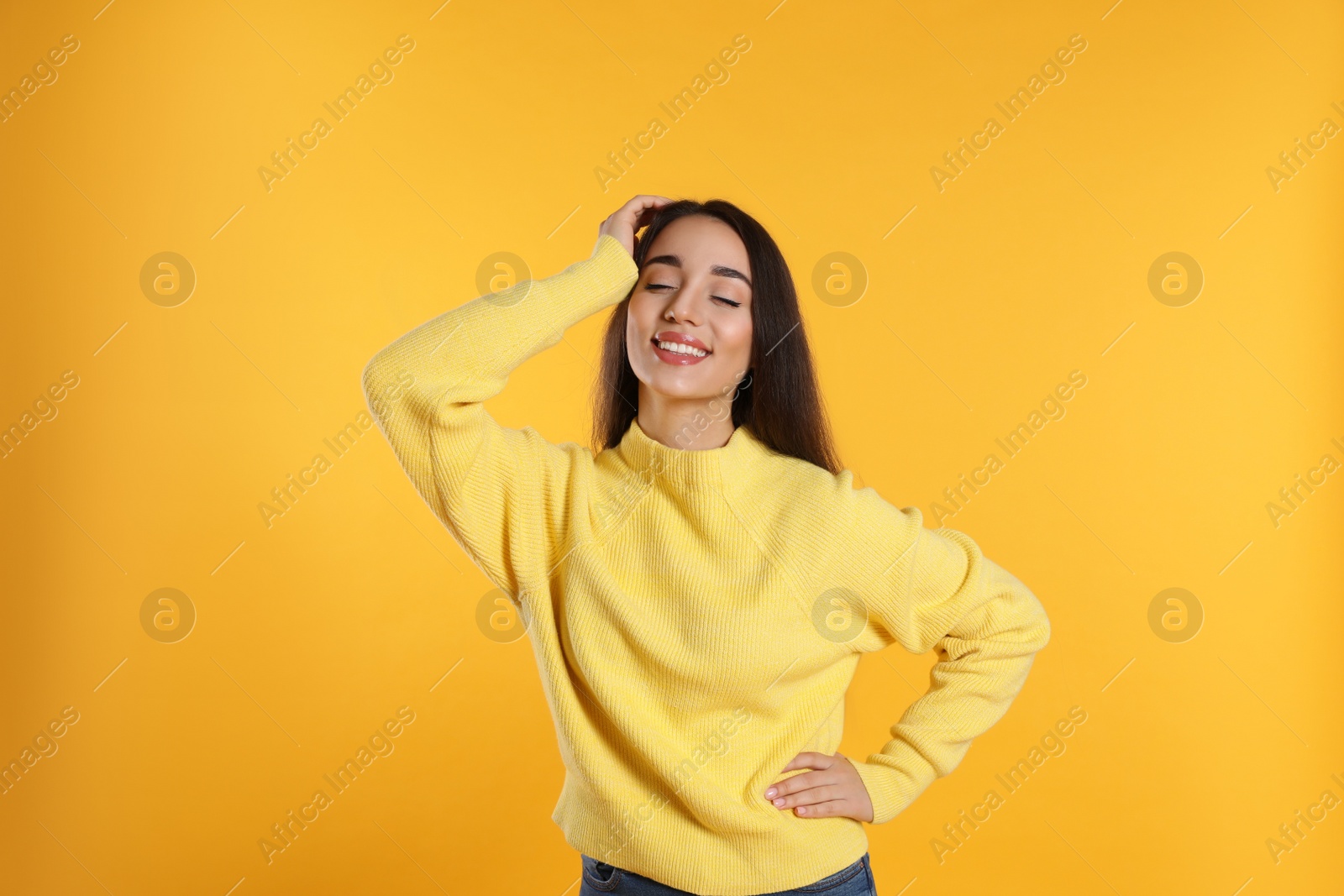 Photo of Beautiful young woman wearing warm sweater on yellow background