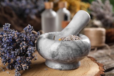 Mortar with pestle and lavender flowers on wooden table, closeup. Medicinal herbs