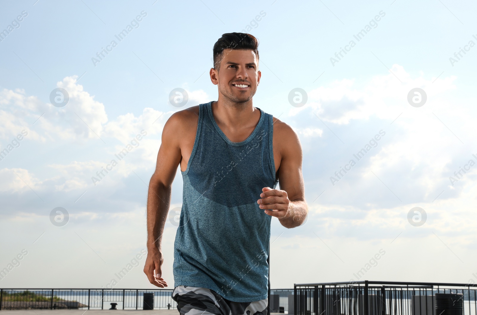 Photo of Handsome man in sportswear running outdoors on sunny day