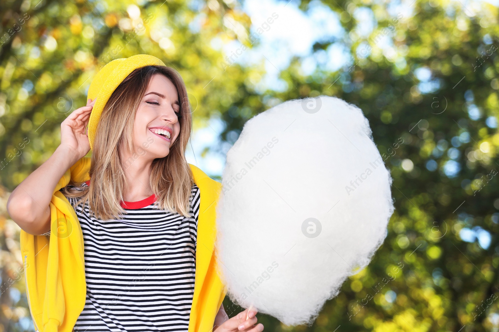 Photo of Young cheerful woman having fun with  cotton candy in park