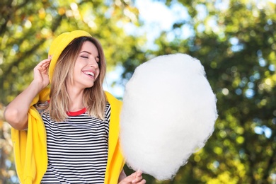 Photo of Young cheerful woman having fun with  cotton candy in park