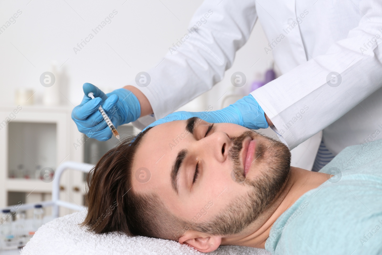 Photo of Young man with hair loss problem receiving injection in salon