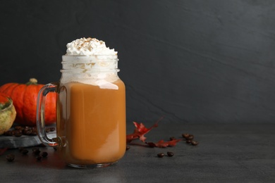 Photo of Mason jar with tasty pumpkin spice latte on grey table, space for text