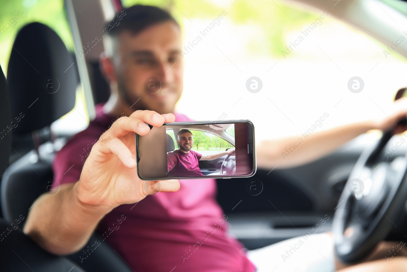 Photo of Happy young man taking selfie in car