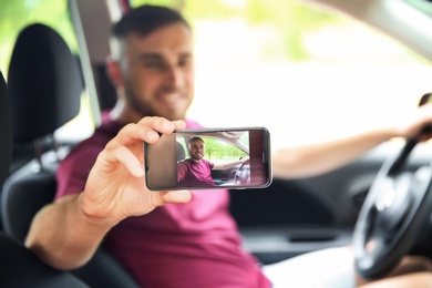 Happy young man taking selfie in car