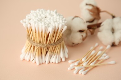 Photo of Many cotton buds and flowers on beige background, closeup