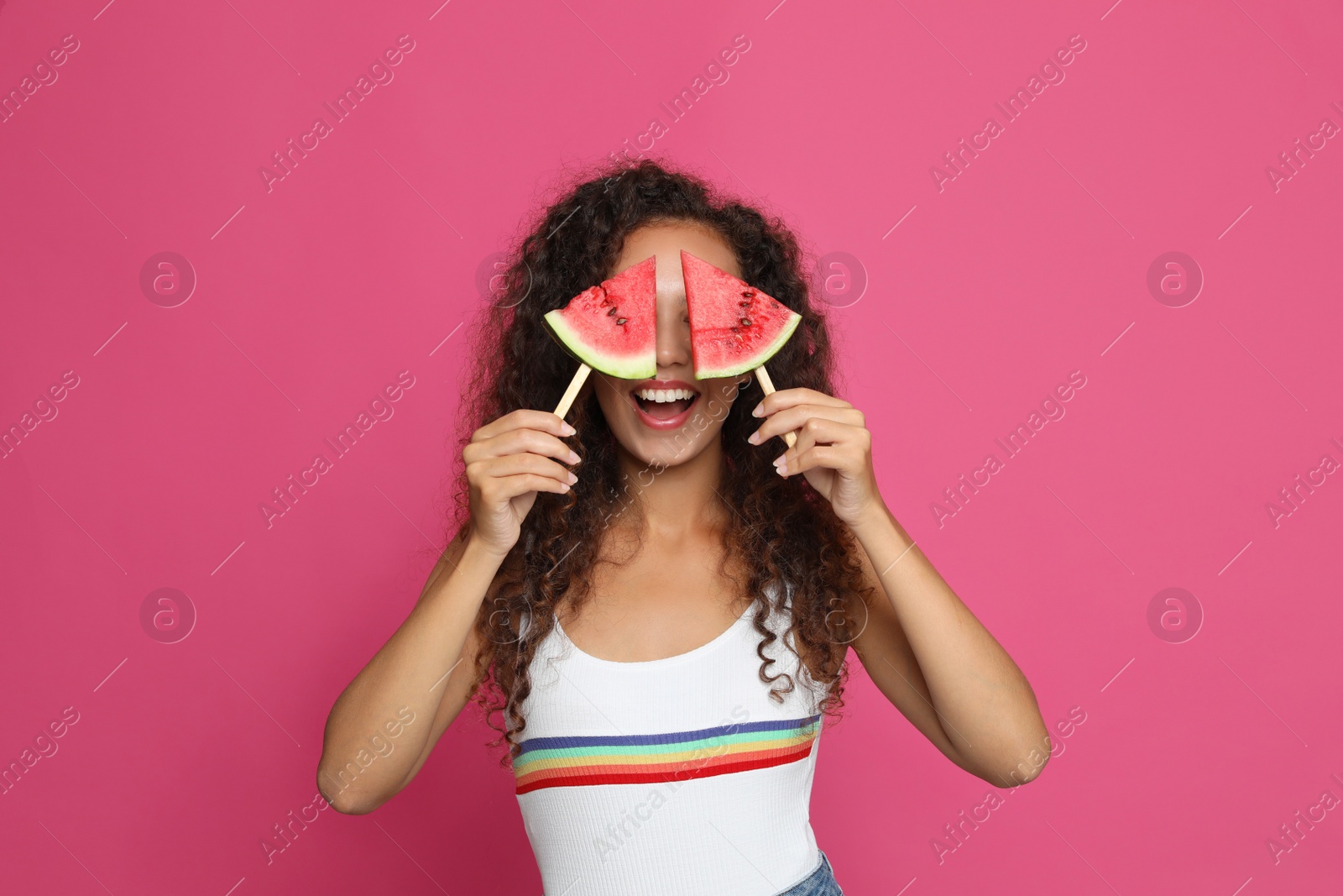 Photo of Beautiful young African American woman with pieces of watermelon on crimson background