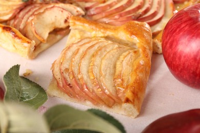 Piece of tasty apple pie, fresh fruits and green leaves on table, closeup