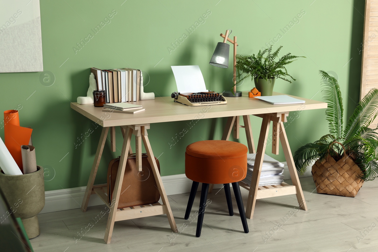 Photo of Writer's workplace with typewriter on wooden desk near pale green wall in room