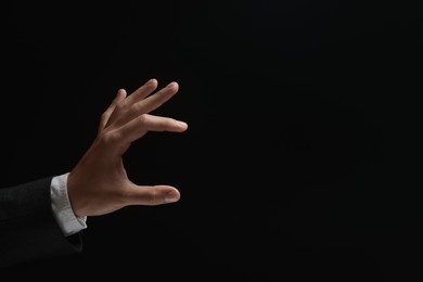 Photo of Man holding something in hand on black background, closeup. Space for text