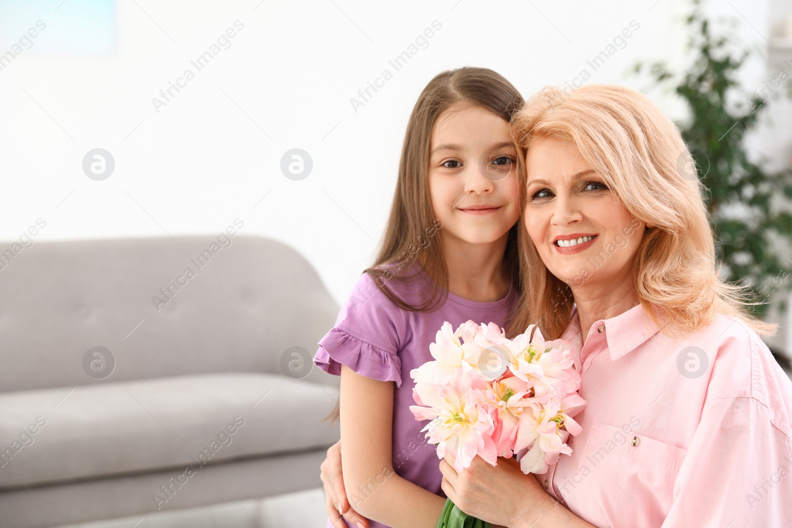 Photo of Little daughter congratulating her mature mom at home, space for text. Happy Mother's Day