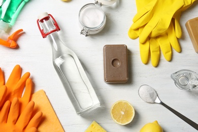 Photo of Flat lay composition with vinegar and cleaning supplies on white wooden background