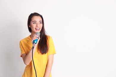 Photo of Young woman in casual clothes posing with microphone on color background. Space for text