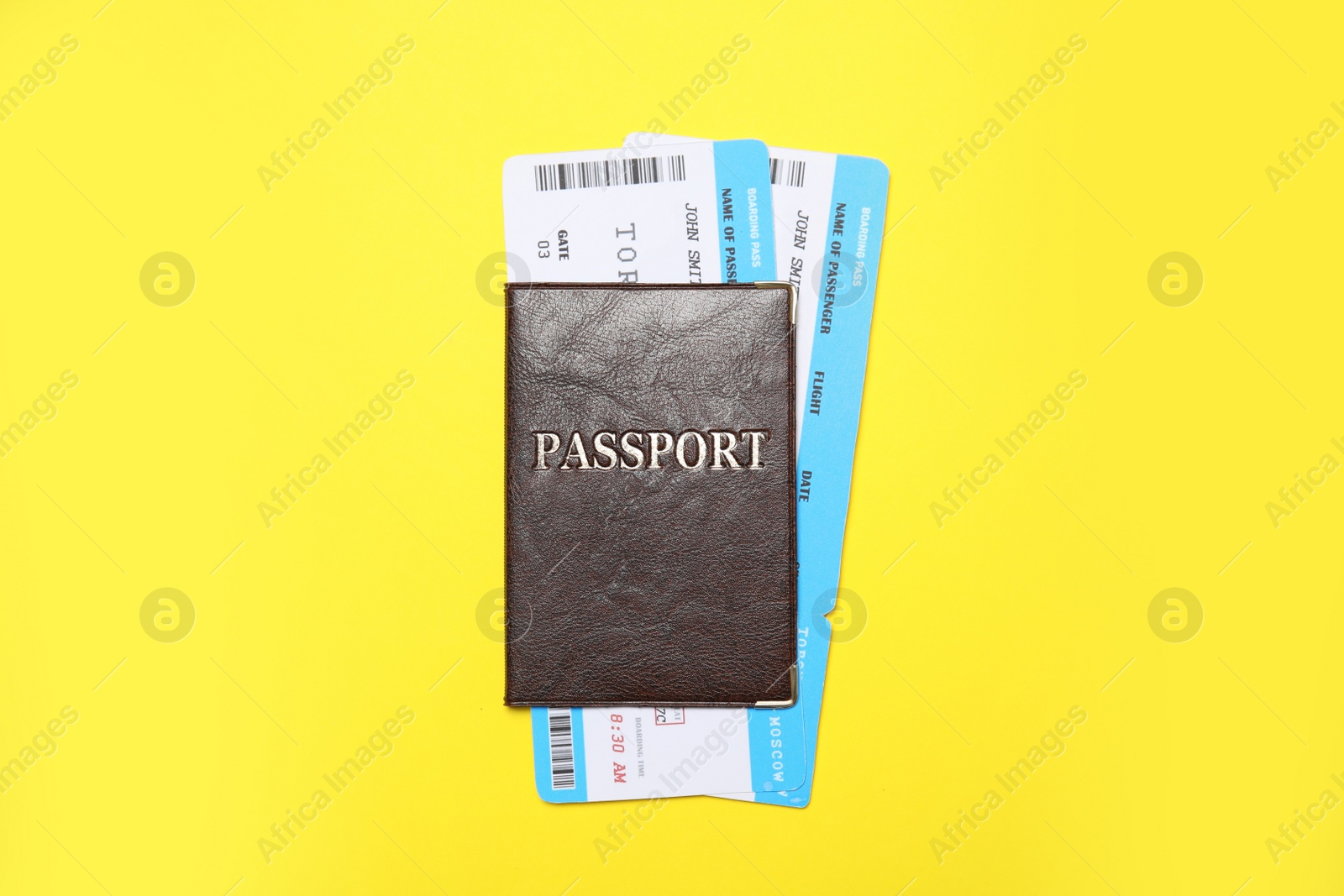 Photo of Passport with tickets on yellow background, top view