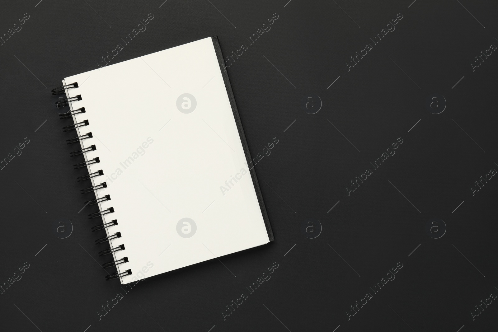 Photo of Blank notebook on black background, top view. Space for text