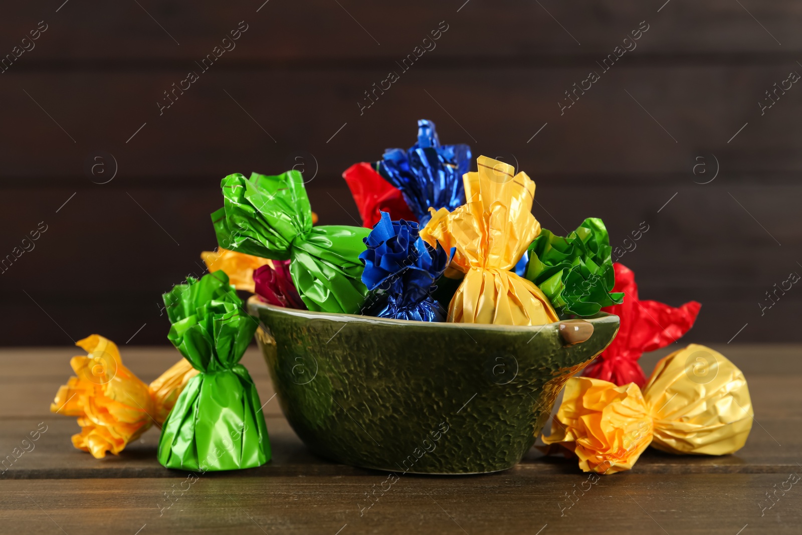 Photo of Candies in colorful wrappers on wooden table