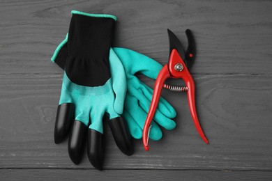 Photo of Pair of claw gardening gloves and secateurs on grey wooden table, top view