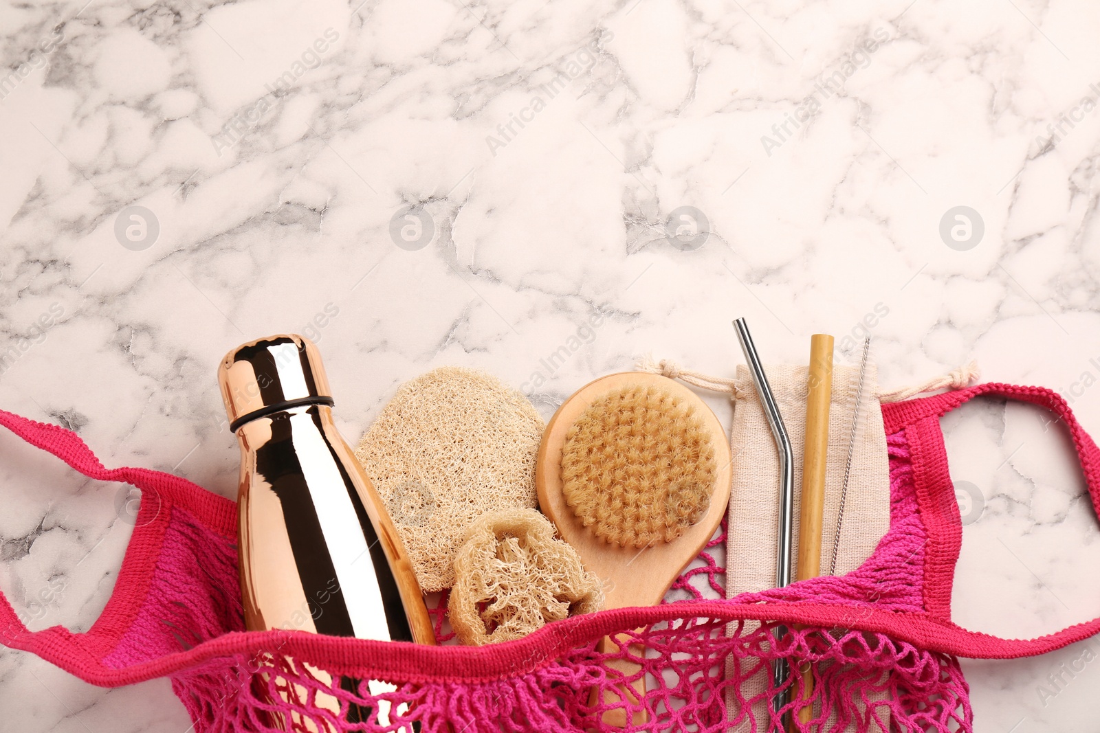 Photo of Net bag with different items on white marble table, top view and space for text. Conscious consumption