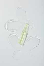 Skincare ampoule on white surface with gel, top view