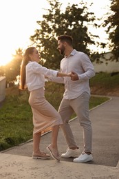 Photo of Lovely couple dancing together outdoors at sunset