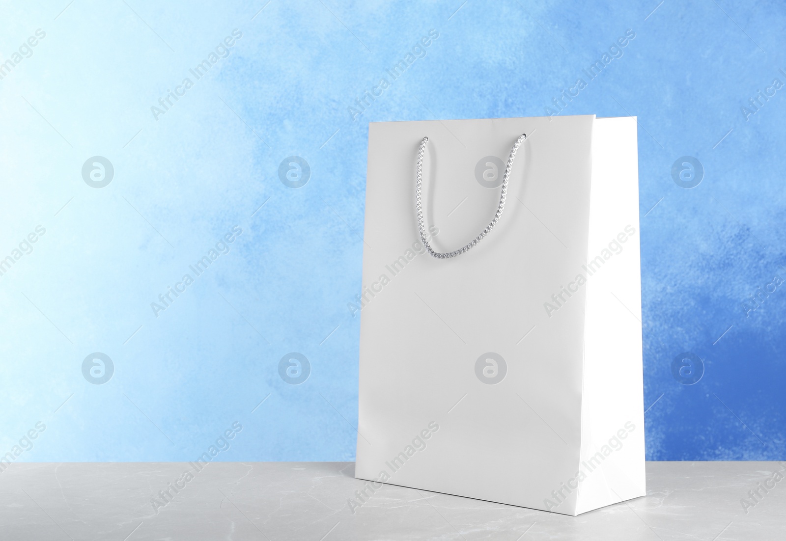 Photo of Mockup of paper shopping bag on table against color background