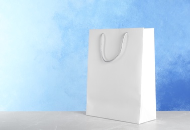 Photo of Mockup of paper shopping bag on table against color background