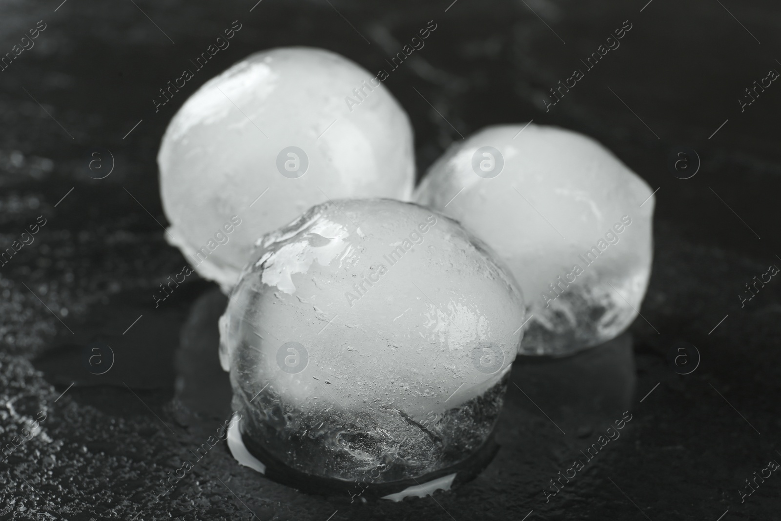 Photo of Melting ice balls on black table, closeup