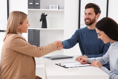 Photo of Real estate agent shaking hands with client at table in office