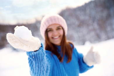 Young woman playing snowballs outdoors, focus on hand. Winter vacation