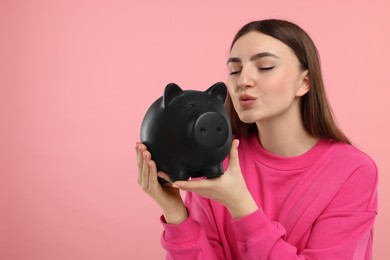 Photo of Woman with piggy bank on pink background, space for text