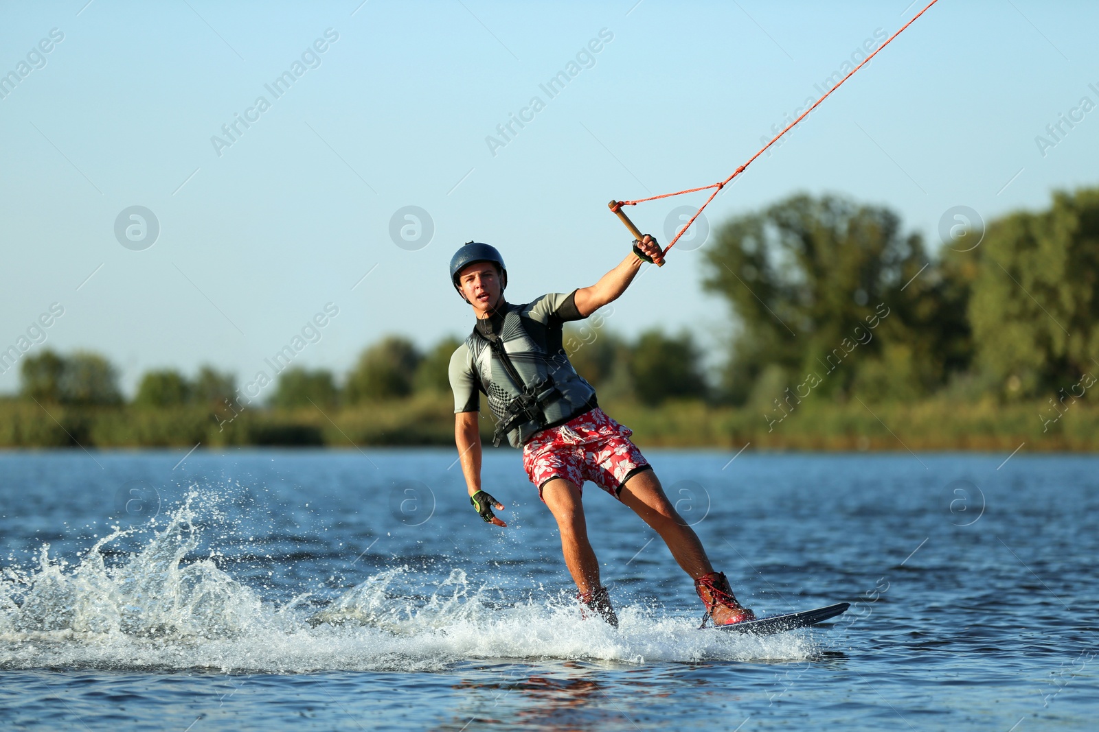 Photo of Teenage boy wakeboarding on river. Extreme water sport