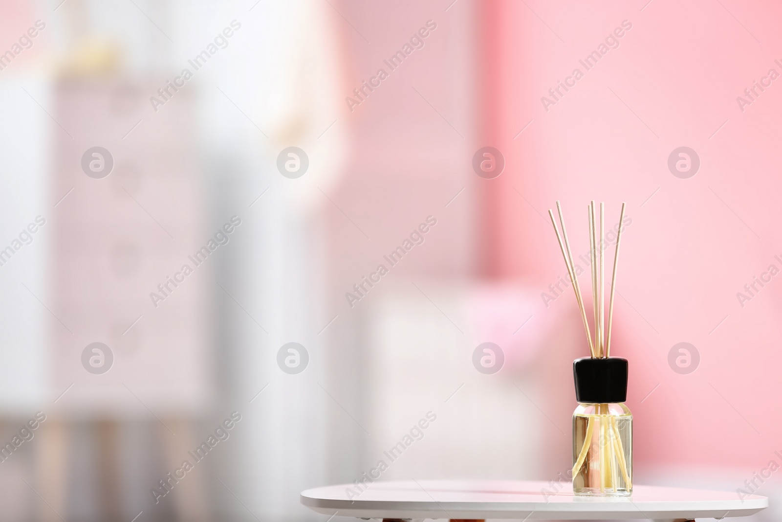 Photo of Aromatic reed air freshener on table against blurred background