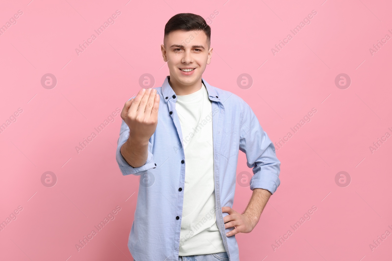 Photo of Handsome man inviting to come in against pink background