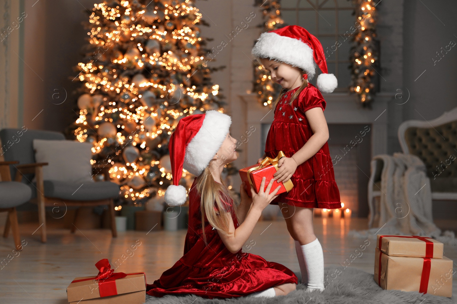 Photo of Cute little children wearing Santa hats with Christmas gift at home