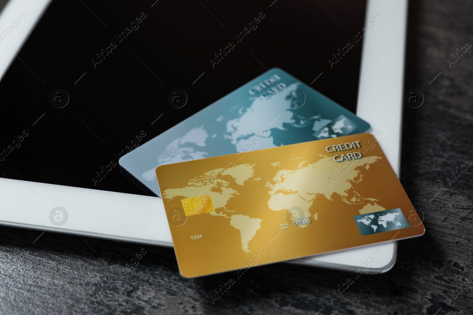 Photo of Credit cards and tablet on grey table, closeup