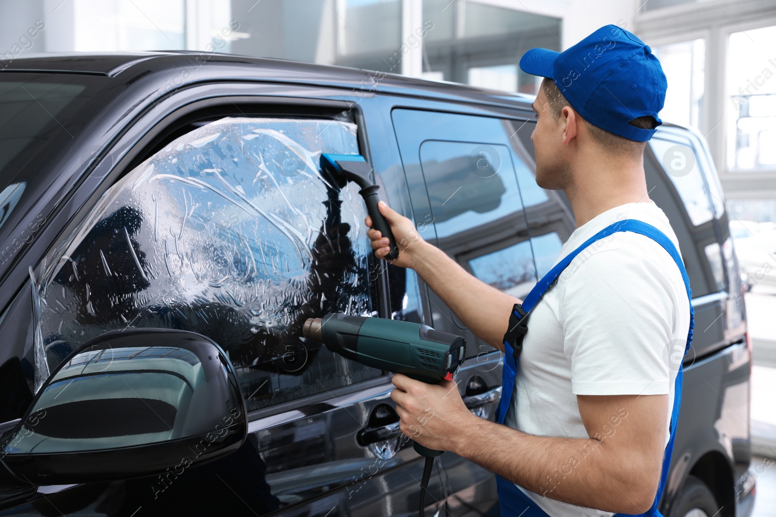 Photo of Worker tinting car window with foil in workshop