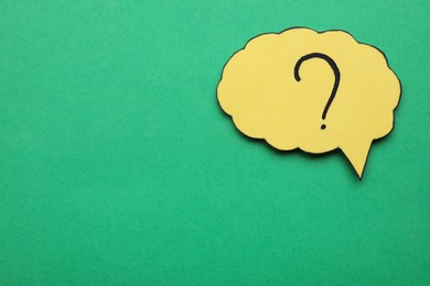 Photo of Paper speech bubble with question mark on green background, top view. Space for text