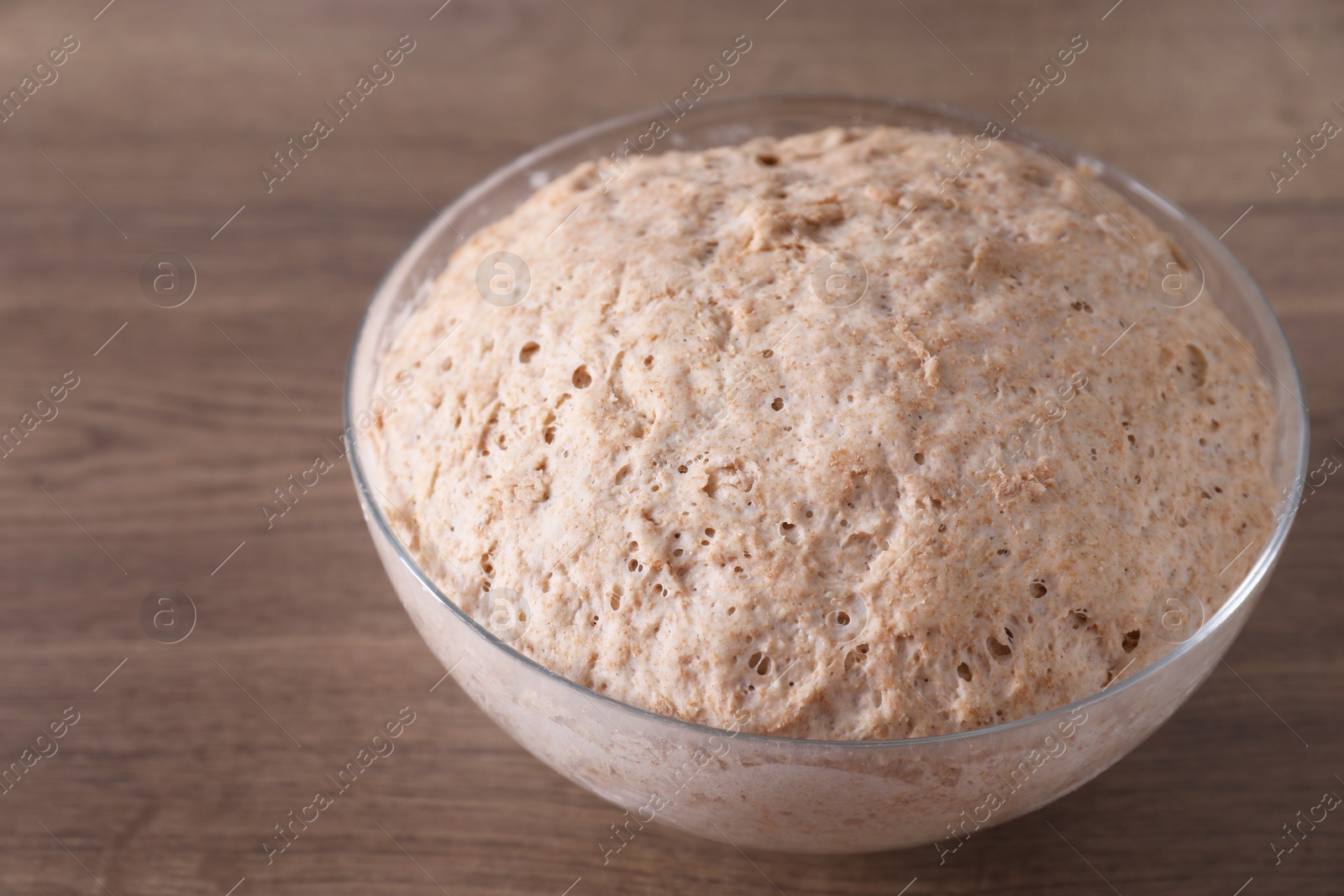 Photo of Fresh sourdough in bowl on wooden table, closeup