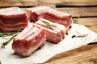 Photo of Raw ribs with rosemary on wooden table, closeup