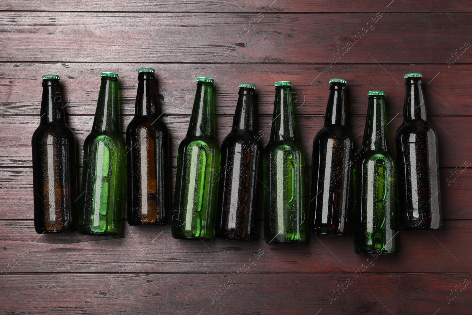 Photo of Glass bottles of beer on wooden background, flat lay