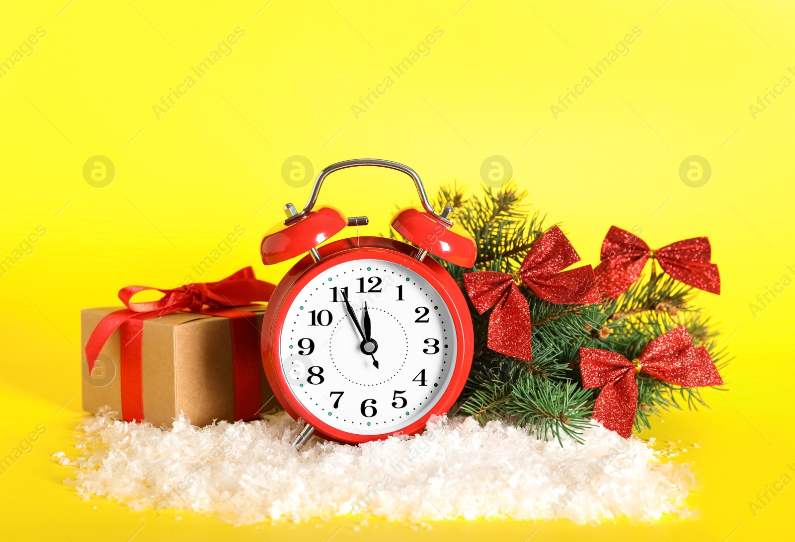 Photo of Alarm clock with Christmas decor on yellow background. New Year countdown