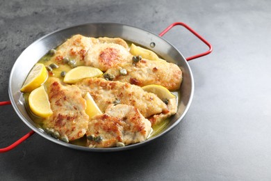 Delicious chicken piccata with lemons on grey table. Space for text