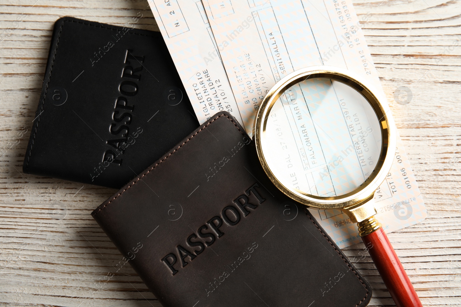Photo of Passports, tickets and magnifying glass on wooden table, top view. Travel agency